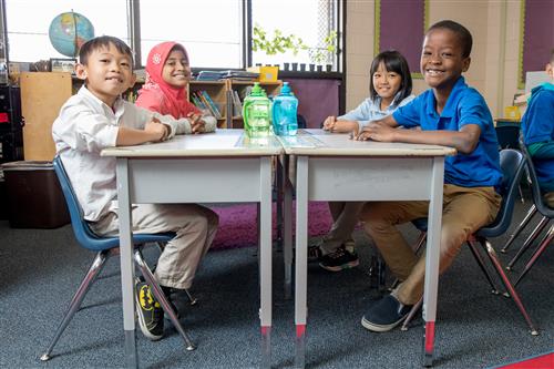 Four elementary students sitting around desks 